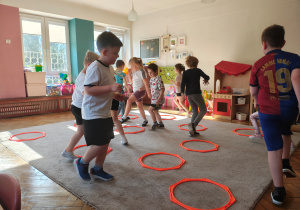 Przedszkolaki biegają po dywanie pmiędzy pomarańczowymi ośmiokątami.