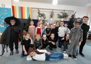 Przedszkolaki przebrane za Jasia i Małgosię, wilka, przebrane na czarno, przebrane za czarownicę. Chłopiec przebrany za drwala leży na dywanie.