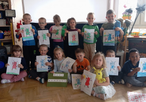 Przedszkolaki stojąc i siedząc trzymają pokolorowane obrazki "Baby Beetles".