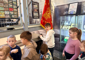 Chłopiec stoi przy maszynie do kierowania starym tramwajem. Przed nim stoją dzieci.