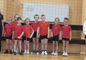 Przedszkolaki wraz z uczennicami stoją na sali gimnastycznej.