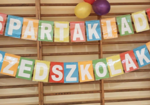 Napis Spartakaida Przedszkolaków i balony powieszone na drabinkach.