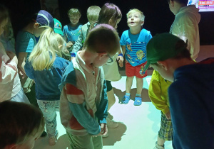 Przedszkolaki stojące na interaktywnej macie w Planetarium.