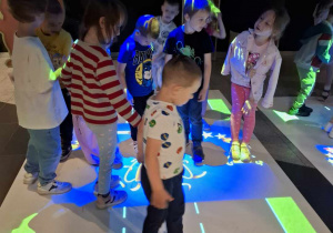 Przedszkolaki stojące na interaktywnej macie w Planetarium.