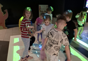 Przedszkolaki stojące na interaktywnej macie w Planetarium.