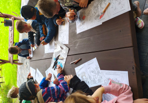 Przedszkolaki kolorujące obrazki z leśnymi zwierzętami i roślinami.