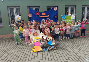 Przedszkolaki wraz z nauczycielkami prowadzącymi Dzień Przedszkolaka i Pasowanie na Przedszkolaka pozują do zdjęcia na tarasie przedszkolnym.