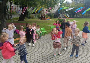 Przedszkolaki tańczą indywidualnie i w parach na tarasie przedszkolnym.
