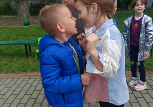 Chłopiec z dziewczynką tańczą w parze. W tle inne dzieci.