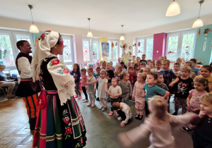 Mężczyzna z kobietą stoją w strojach regionalnych. Przed nimi stoją dzieci.
