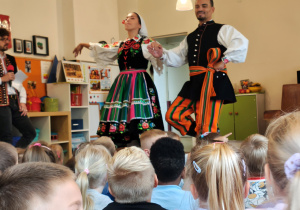 Mężczyzna z kobietą stoją w strojach regionalnych trzymając się za ręce..