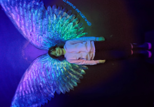 Dziewczynka ze skrzydłami w ultrafioletowym świetle.