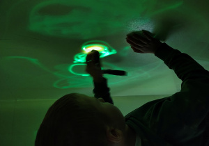 Chłopiec rysuje światłem na ścianie.