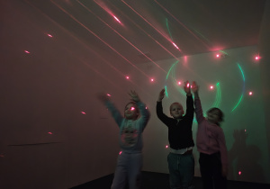 Troje dzieci podskakuje, aby dosięgnąć laserów.