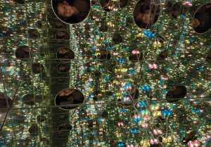 Chłopiec w oświetlonym kolorowymi światełkami pudle z luster.