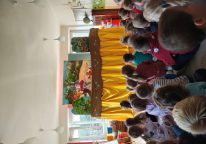 Przedszkolaki siedzą tyłem na dywanie. Przed nimi scenografia i kukła słonia.