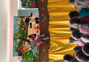 Przedszkolaki siedzą tyłem na dywanie. Przed nimi scenografia i kukły słonia, bobra i sroki.