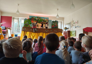 Przedszkolaki siedzą tyłem na dywanie. Przed nimi scenografia i kukły słonia, bobra i sroki.