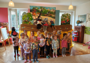 Przedszkolaki z grupy I stoją na tle scenografii i kukiełek sroki, bobra i słonia.