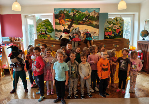 Przedszkolaki z grupy III stoją na tle scenografii i kukiełek sroki, bobra i słonia.