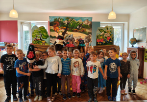 Przedszkolaki z grupy II stoją na tle scenografii i kukiełek sroki, bobra i słonia.