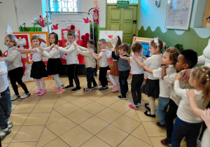 Przedszkolaki ubrane na galowo stoją tworząc węża.