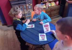 Trzech chłopców ogląda ulotki przy stoliku.