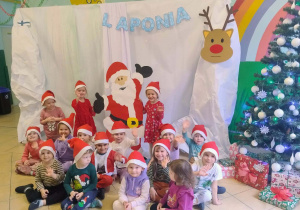 Przedszkolaki z grupy I, w czapkach Mikołaja pozują na tle dekoracji - Laponii.