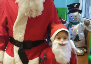 Chłopiec w przebraniu Mikołaja stoi obok Mikołaja.