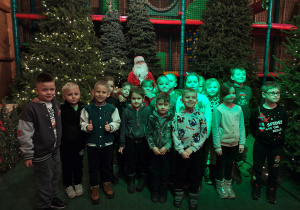 Przedszkolaki stoją przed saniami Mikołaja. W saniach siedzi Mikołaj.