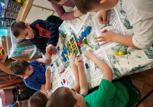 Przedszkolaki wyklejają flagę Francji bibułą.