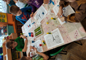 Przedszkolaki wyklejają flagę Francji bibułą.