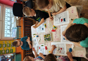 Przedszkolaki wyklejają flagę Francji bibułą.