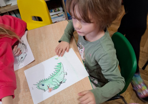 Dziewczynka koloruje obrazek smoka.