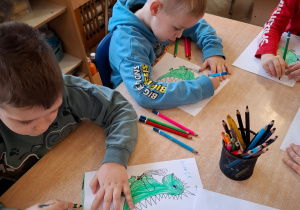 Chłopcy kolorują obrazki smoków.