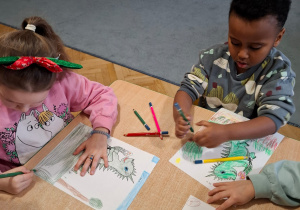 Chłopiec i dziewczynka kolorują obrazki smoków.