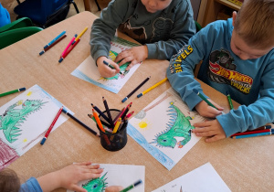 Chłopcy kolorują obrazki smoków.