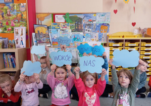 Przedszkolaki trzymają napis "Czyste powietrze wokół nas", w tle obrazki dymów.