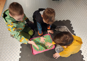 Przedszkolaki siedzą rysując po niebiesko-żółtym ryżu.