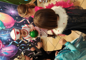 Pięcioro dzieci stoi w kole. Jedna z dziewczynek trzyma piłkę.