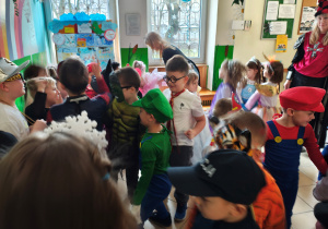 Przedszkolaki przebrane w stroje karnawalowe wspólnie tańczą.