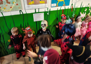 Przedszkolaki przebrane w stroje karnawalowe wspólnie tańczą.