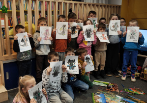 Przedszkolaki stoją i prezentują swoje pokolorowane smoki.