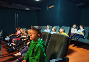 Dzieci siedzące w fotelach w kinie.