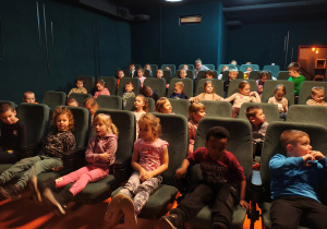 Dzieci siedzące w fotelach w kinie.