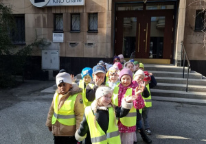 Przedszkolaki w odblaskowych kamizelkach stojące w parach przed kinem Charlie.